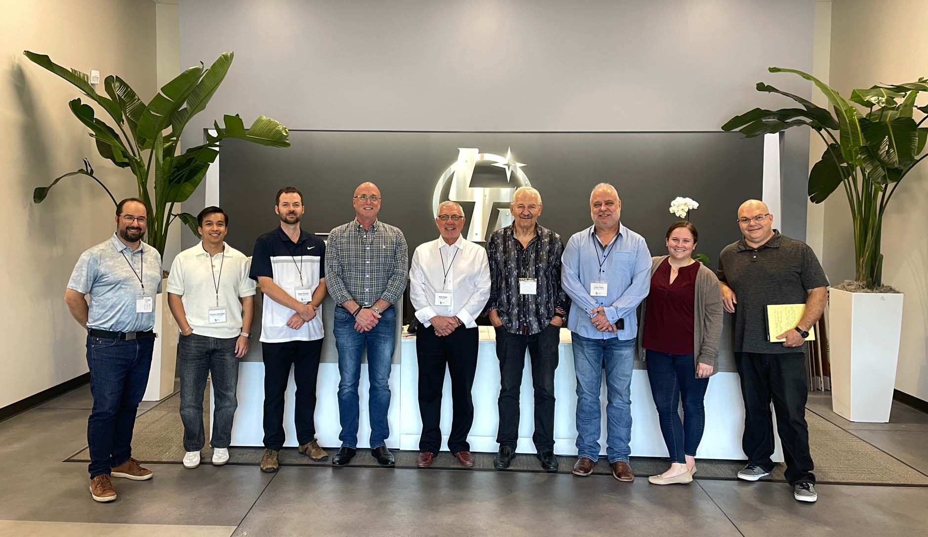 A group of people standing in front of a plant.